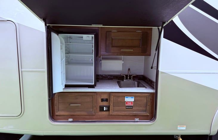 Outdoor Kitchen featuring a beverage refrigerator, wet sink, propane grille hookup and cabinets.