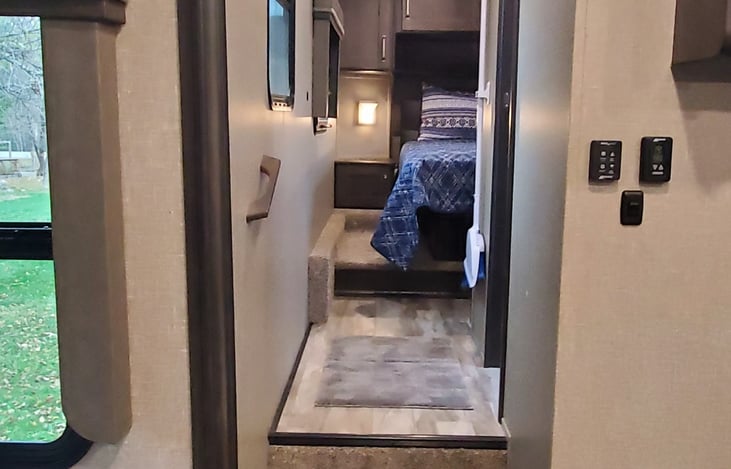 Steps up to private bathroom and residential queen size bed with sliding barn door for complete privacy