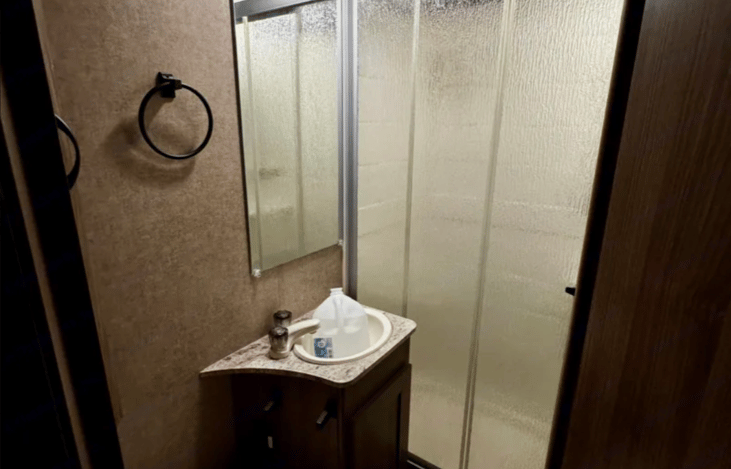 Full bathroom with toilet, sink and indoor shower featuring cold and hot water.
