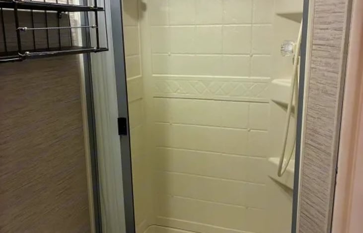 Private rear corner bathroom including a 24" x 36" shower with a skylight, foot-flush toilet, and a counter sink with medicine cabinet.