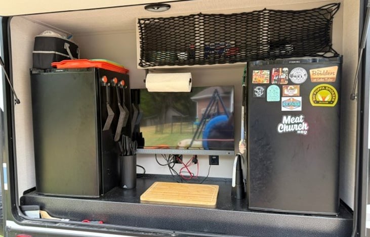 Outdoor Kitchen. 2 refridgerators, 1 TV (firestick included), Cooking utinsels, trays, paper plates/bowls, plastic forks/spoons/knives, Foil, Gloves, cutting board, ect..