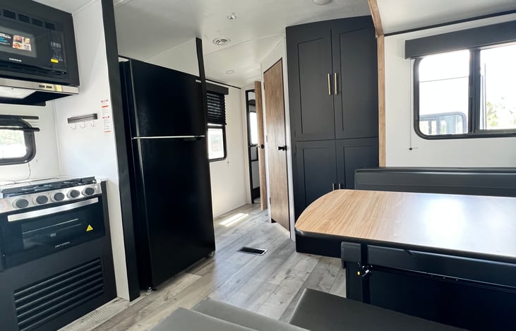 Kitchen with a full refrigerator. a table that seats 4 and converts to a full bed.