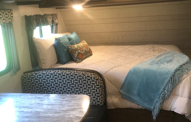 Standing in middle of camper.  Queen bed and dinette table