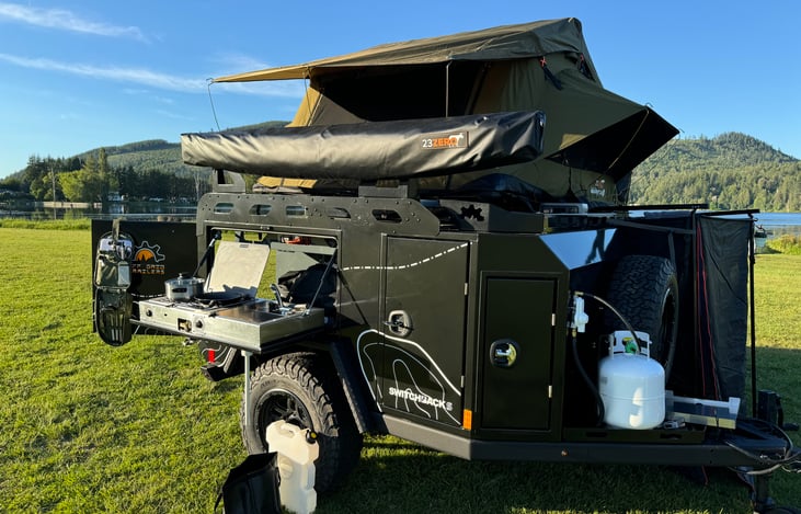 Cooking side of trailer with 2 burner domestic propane stove and sink with hot and cold water.