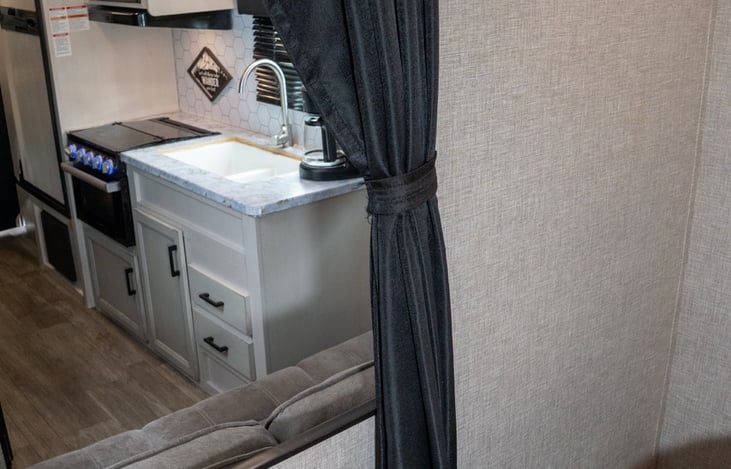 Primary suite features a black out privacy curtain to shut the bedroom off from the rest of the RV.