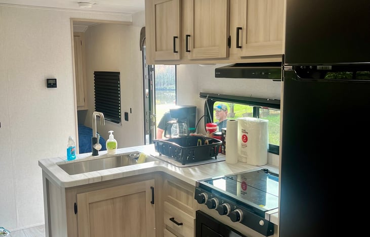 Picture of stove top, microwave, and dish sink. Coffee Maker, Dish Set, Cookware All Included!