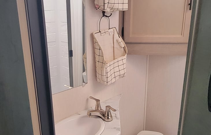 It features an overhead medicine cabinet and hanging storage compartments.