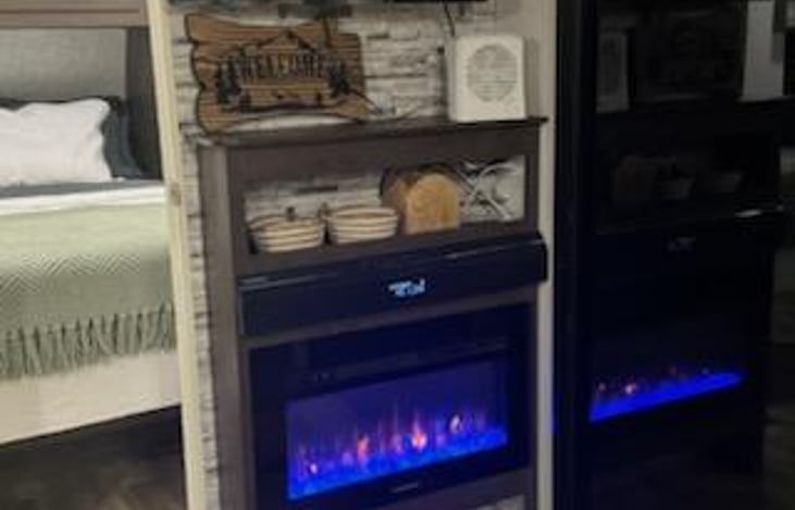 Electric fireplace that color changes as you wish, stereo system, air purifier, mints, remotes and welcome sign next to sliding glass door. Flatscreen tv.