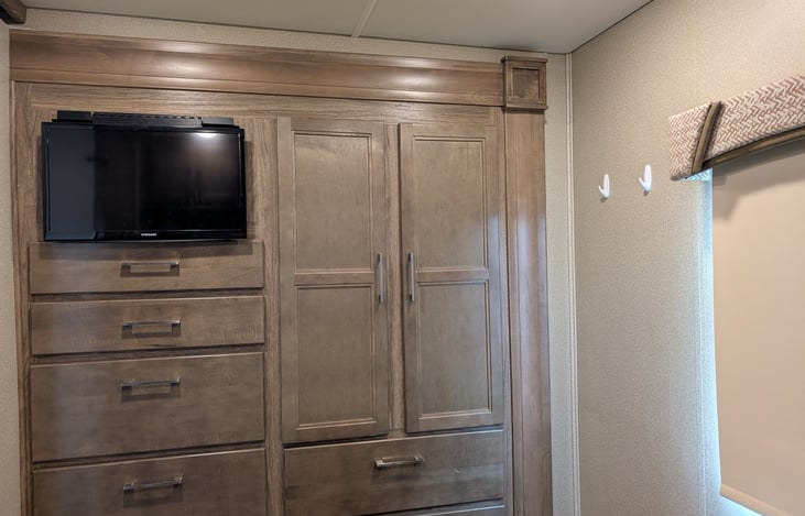 Built-in entertainment center with Samsung TV, multiple drawers, and wardrobe space keeps everything organized. Perfect for movie nights or storing your vacation essentials.
