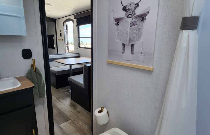Fun decor in the bathroom makes this space fun! Under the sink is extra toilet paper, extra hand towel, and bath towels.