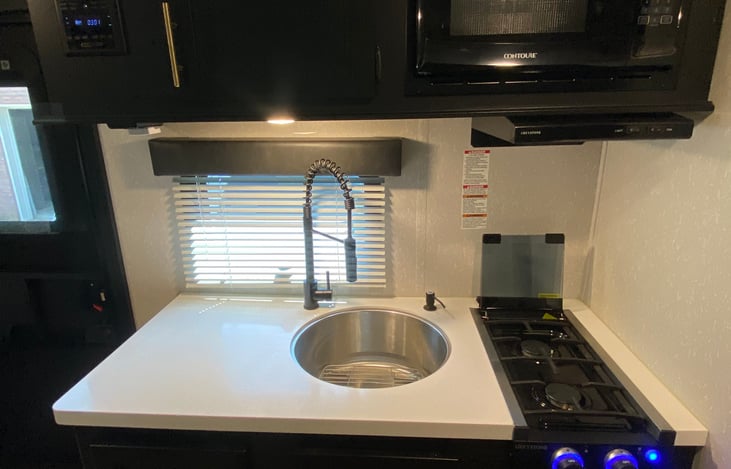 Two burner stove top, microwave, and deep well sink.