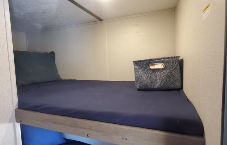 Bunk Beds with sheets, storage baskets, standard pillows and decorative pillows featured in the Glamping Package Addon