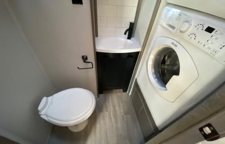 Half bath with oval toilet, dryer above washer.