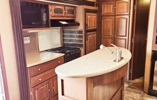 Large RV with outdoor kitchen, fireplace, and TVs