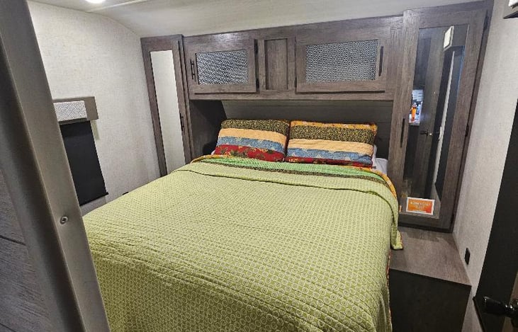 Master bedroom with queen sized bed and storage compartments.