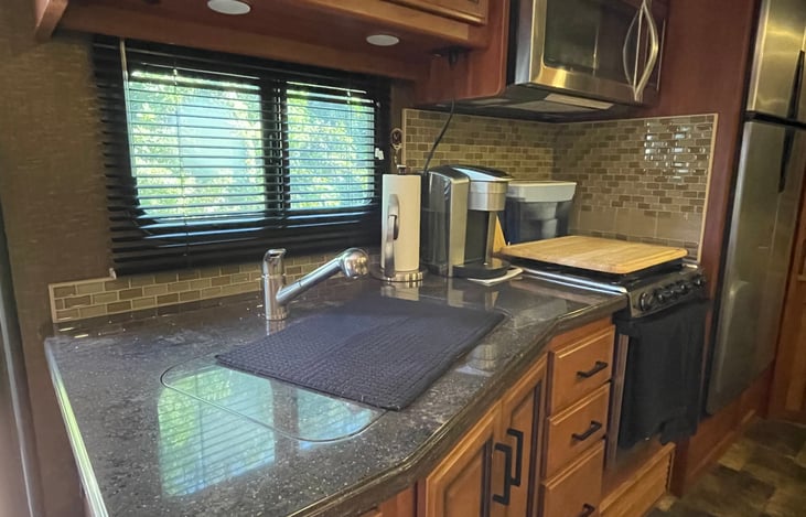 Kitchen includes propane range and oven, convection microwave, Keurig coffee maker, and large refrigerator. All Stainless appliances.