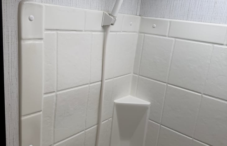 Clean and convenient private bathroom featuring a foot-flush toilet, standing shower, and dedicated storage to keep your essentials organized.