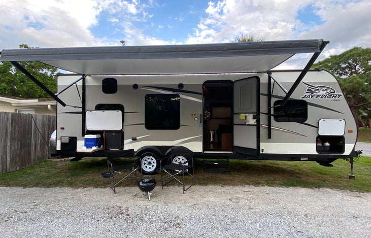 The 13' Electric Awning, LED Awning Accent Light, 2 Provided Camping Chairs, Outside Cocktail Bar, and Provided BBQ Grill make for an excellent camping experience.