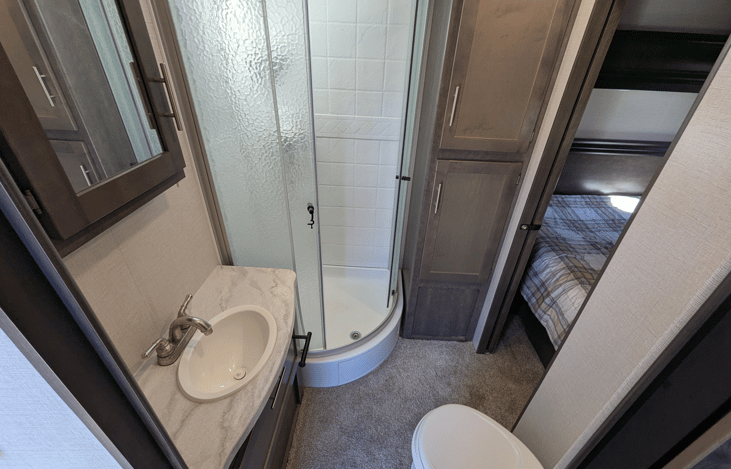 Bathroom with storage, and a tall double-glass shower.