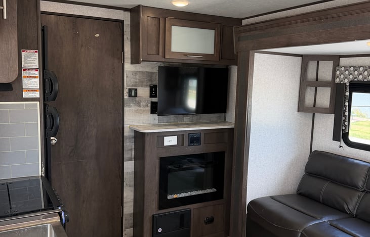 Open-concept living area featuring a mounted flat-screen TV and cozy built-in fireplace.