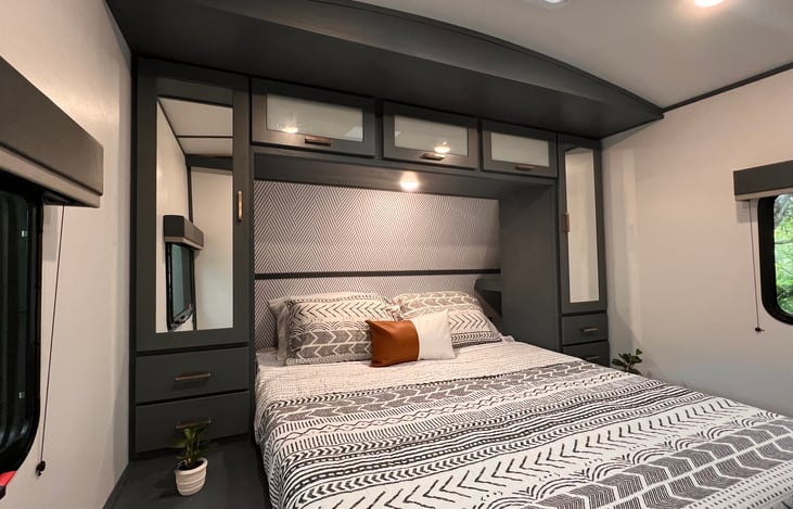 The primary bedroom is appointed with a queen sized bed, cozy bedding, reading lamps and plenty of storage!