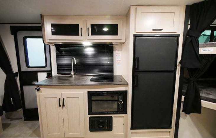 The convenience of a fully functional kitchen includes a refrigerator with freezer, microwave, full size sink, 2 burner stove top, pots, pans, plates, utensils, garbage bags and Keurig Coffee Maker.