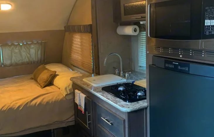 A slide-out galley houses the primary kitchen block to maximize interior walking space. The galley is equipped with a 4.2 cu. ft. 3-way refrigerator, a two-burner range, and a microwave.