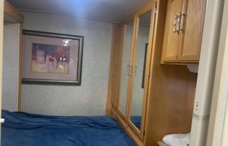 Walk around queen size bed with large cabinet and 2 windows with curtain and private door with Slide siding