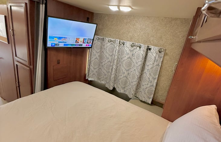 Bedroom with mounted TV. Queen bedding provided.