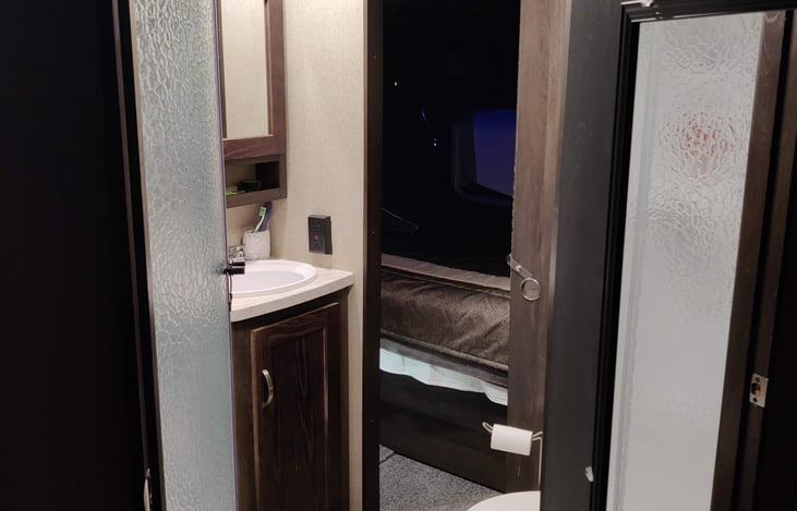 Spacious bathroom with porcelain toilet, sink and large shower.