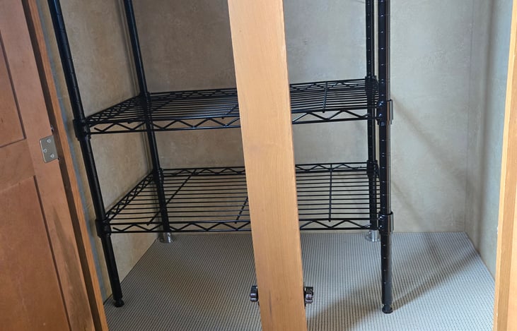 Inside of the closet.  There is a horizontal rod to hang clothes.  The storage rack can be removed to allow for more space to hang clothes.