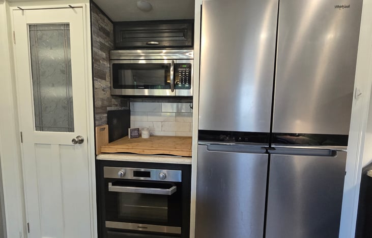 Residential fridge, convection microwave oven, gas range and stove (covered with cutting board in picture), and pantry