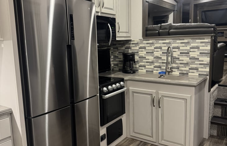 Another view of kitchen sink, oven, refrigerator, microwave.