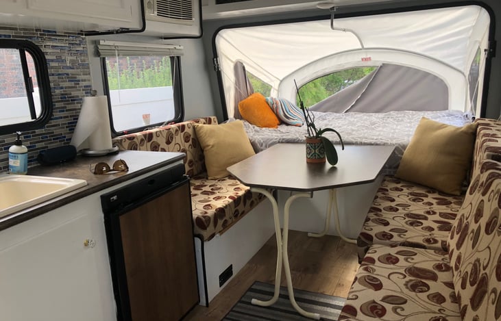 Kitchen sink, small fridge and side wall mounted AC unit, pop up table, pop out bed on front