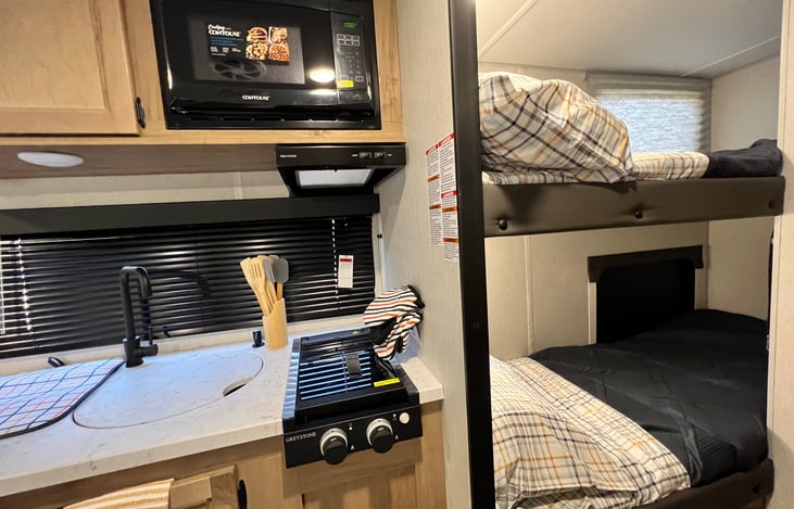 A view of Two burners and the microwave with the bunkbeds