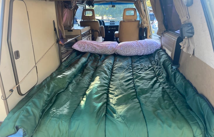 Lower sleeping area, viewed from open tailgate.  Bench seat folded flat to complete the bed platform.