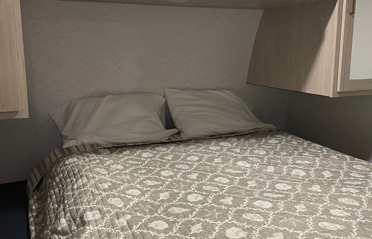 Queen size bed in bedroom with door to separate from main living area.