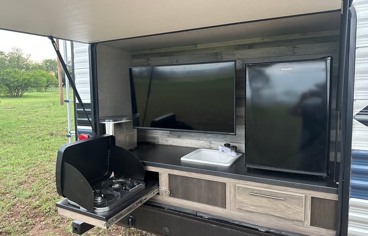 Our door kitchen with refrigerator, freezer, sink, gas grill, ice maker, and 42” smart tv