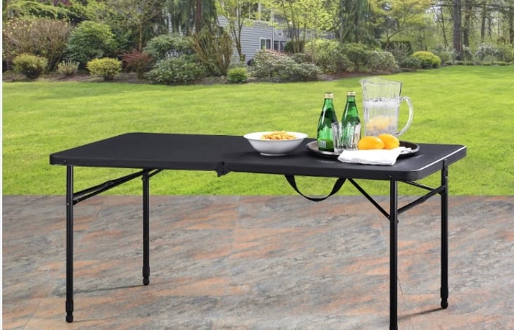 Small black foldable table with adjustable legs provided