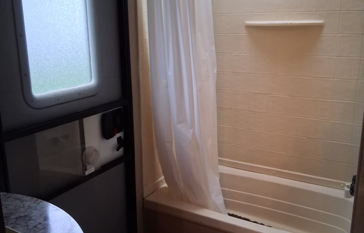 Bathroom with a private door to enter/exit trailer. Includes a shower/tub combo