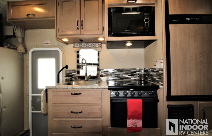 Full kitchen with an 3-burner stove top and oven and a full-size RV fridge and freezer.