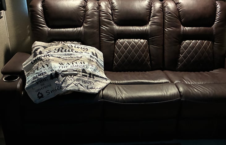Three seater movie theater couch has end recliners and charging ports!! The recliners stretch out fully for sleeping and as you see, we provide extra bedding for recliner and couch sleepers!