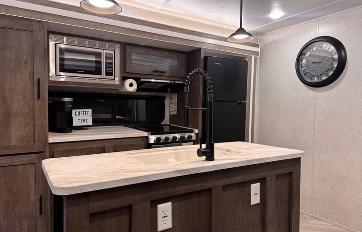 Kitchen area: center island with sink provides plenty of meal prep area, along with a microwave, cooktop, and oven.  Large residential size fridge