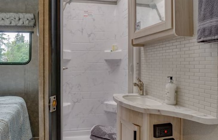 Bathroom has outlet, towel bar, hooks and TP holder.