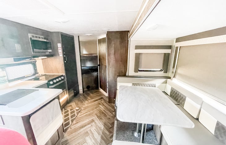 View from walking in the RV you see the dinette, kitchen area, bunk beds and the door to the bathroom.