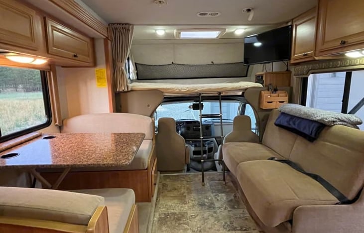 LOOKING FROM KITCHEN STOVE AT COUCH, KITCHEN TABLE, AND UPPER LOFT SLEEPING AREA