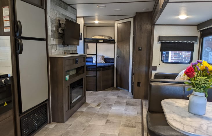 Taken from the bedroom side. L to R: Double door refrigerator, 2 double bunk beds, the bathroom door, closet, sofa, dinette area.