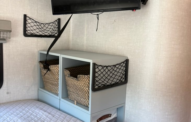 Clothes storage at foot of bed on top and 2 bins slide into the cabinet underneath the TV