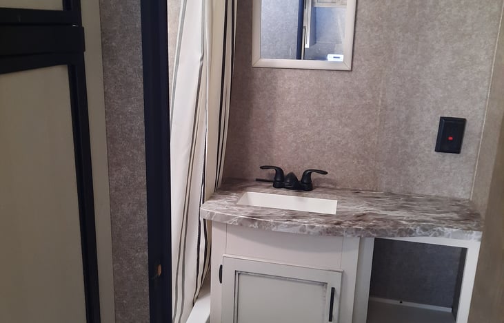 Bathroom with spacious shower, single sink and plenty of storage.