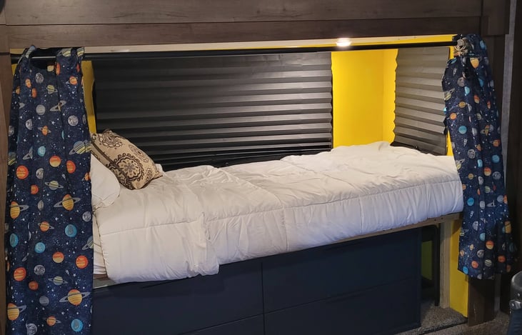 bed with privacy curtains and a 4 drawer dresser.